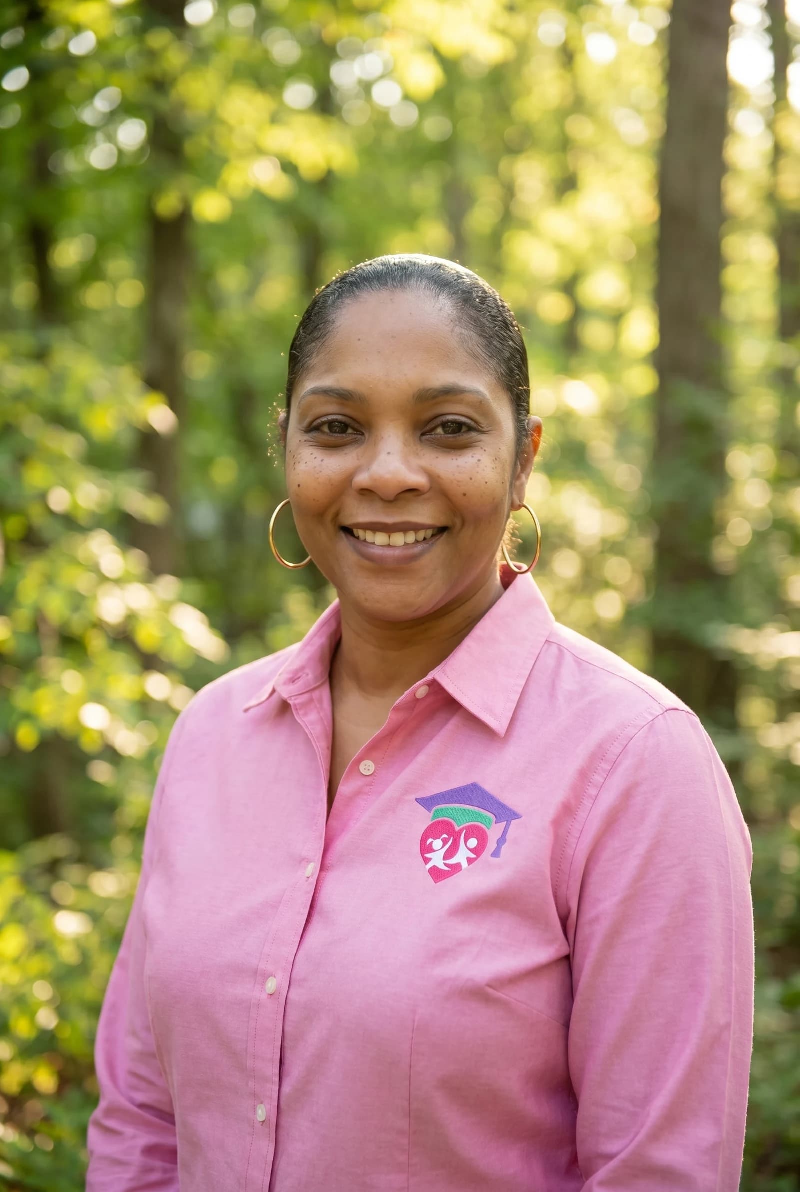 Jamie Wilson, founder of Jewels For Life, smiling outdoors in a pink shirt with the JFL logo